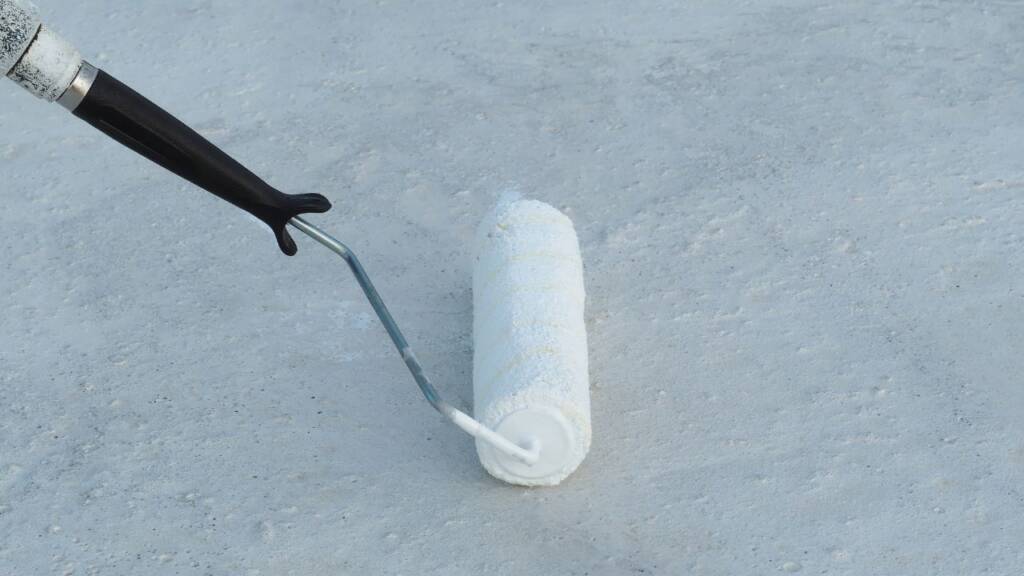 Malowanie powierzchni białą farbą przy użyciu wałka malarskiego