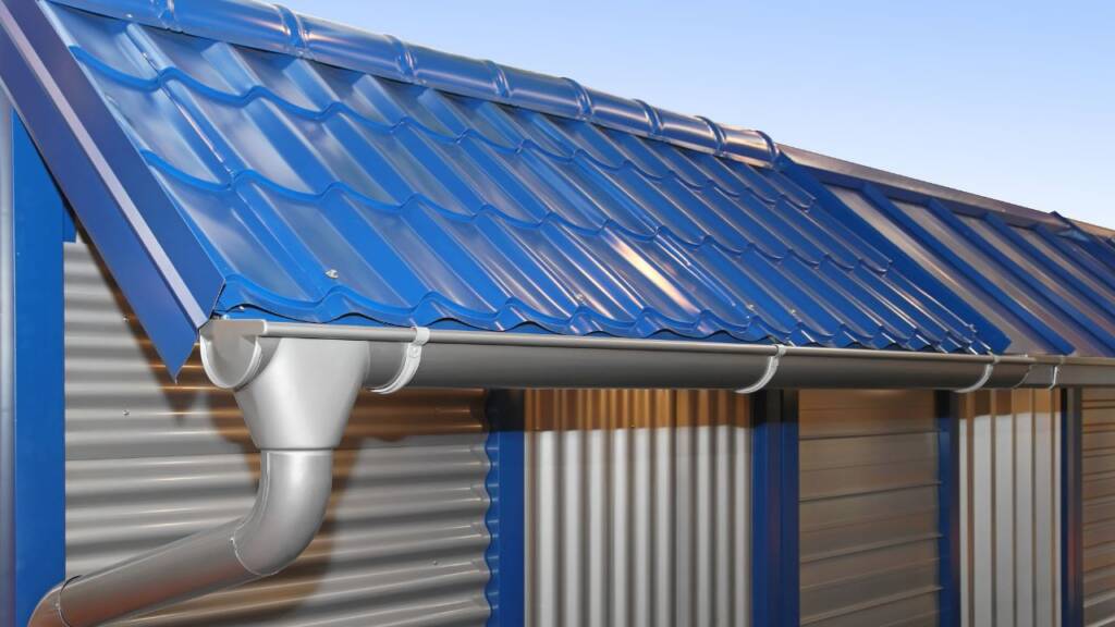 Rynna ocynkowana przy budynku z blachodachówką w kolorze niebieskim