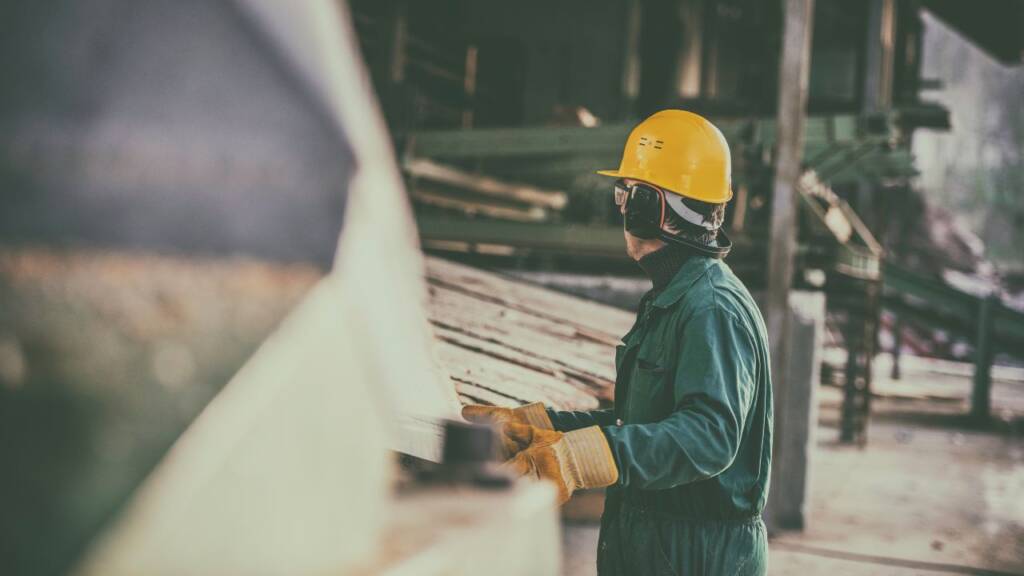 Na obrazku widać mężczyznę, który przenosi drewno